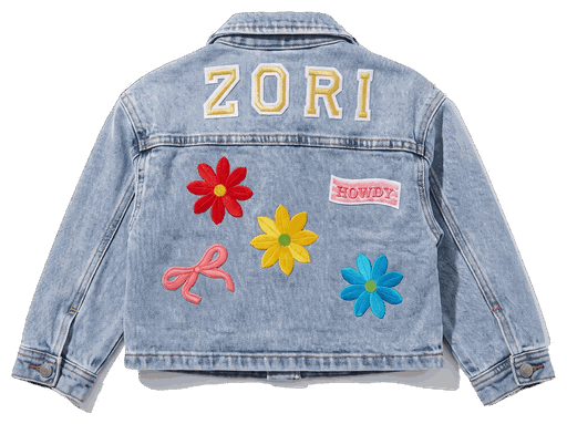The back of a denim jacket, chenille letters across the shoulders and flower and ribbon patches set below them